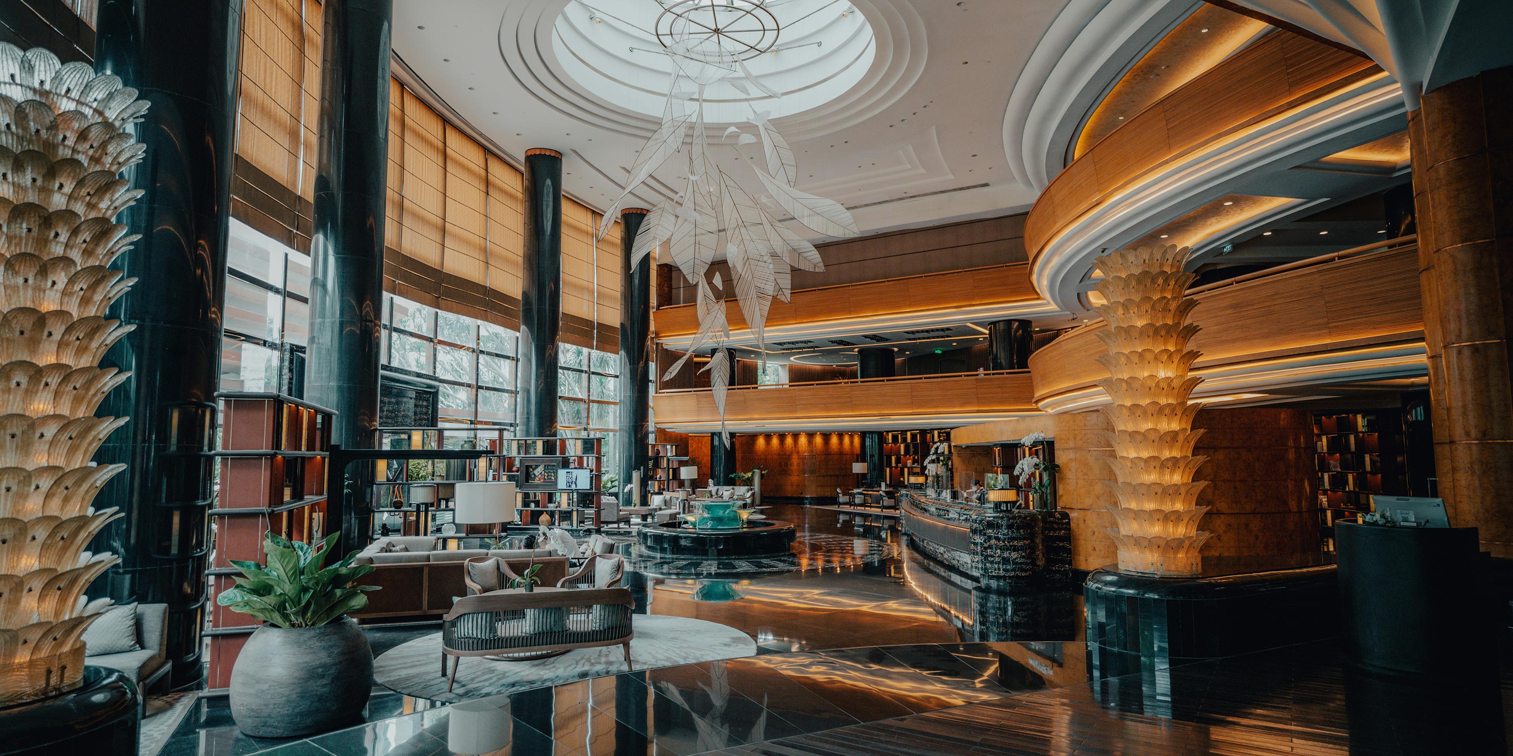 Luxurious hotel lobby with tall columns, seating areas, and a large hanging sculpture