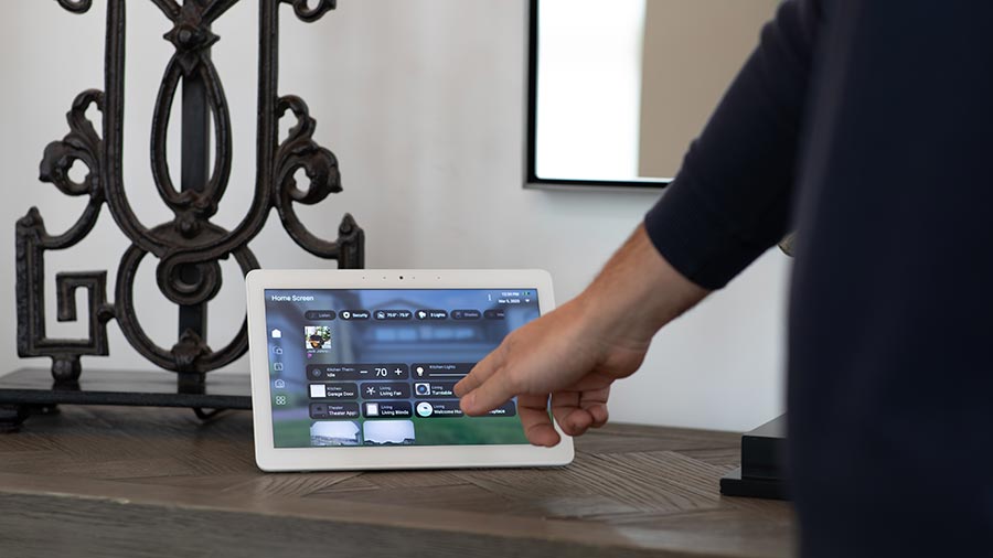 Hand using a touchscreen control panel on a table inside a home