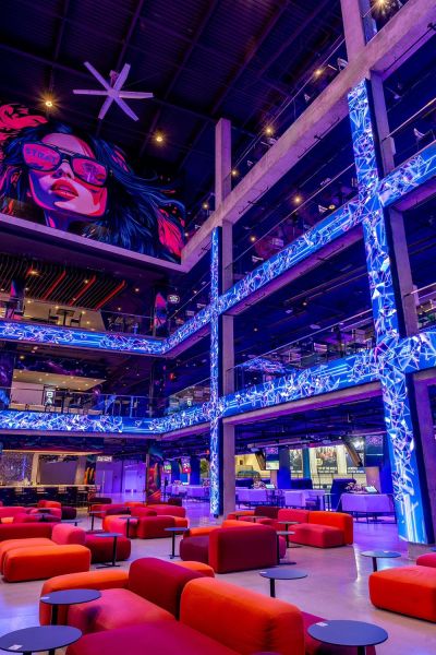 Modern multi-level arcade with red lounge seating and neon blue digital pillars